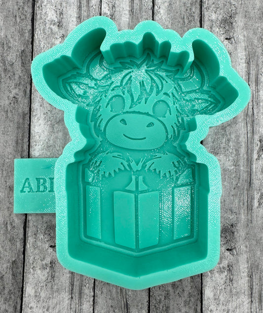 Highland Cow peeking over a Present Freshie Silicone Mold