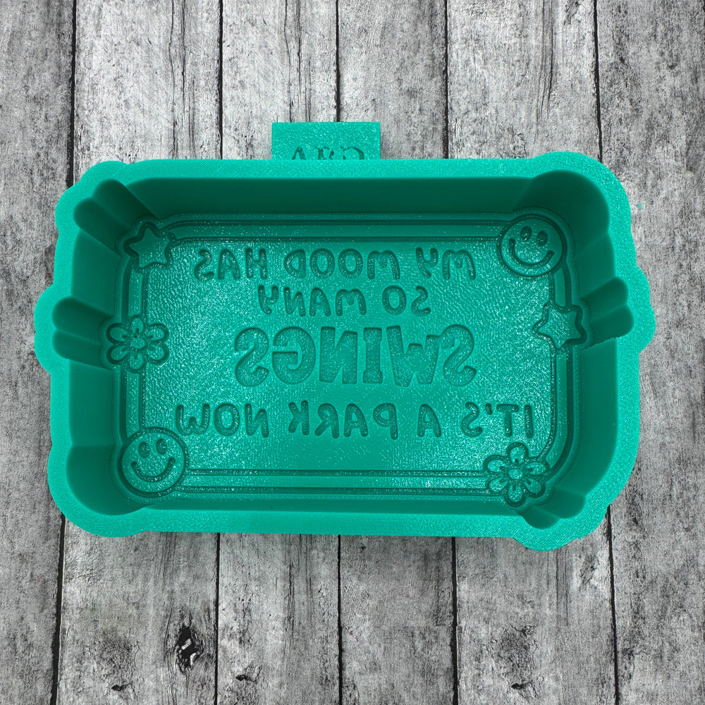 Teal rectangular silicone mold with text on a wooden surface